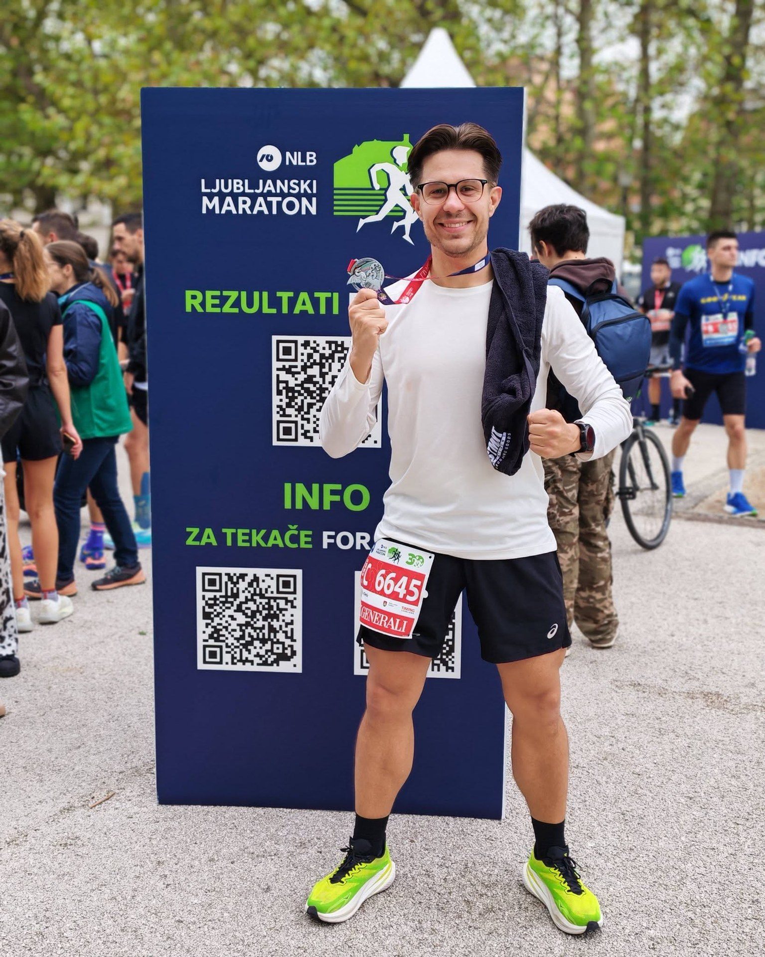 Sudionik utrke s medaljom ispred panoa Ljubljanskog maratona.